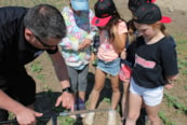 An agriculture volunteer teaches elementary students about soil and its importance for growing food.