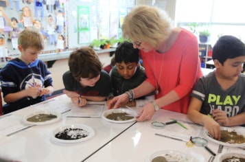 A teacher leads an activity for elementary students to get their hands dirty learning about the importance of soil.