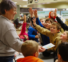 An image of a volunteer at an agricultural event, teaching students about where food comes from.